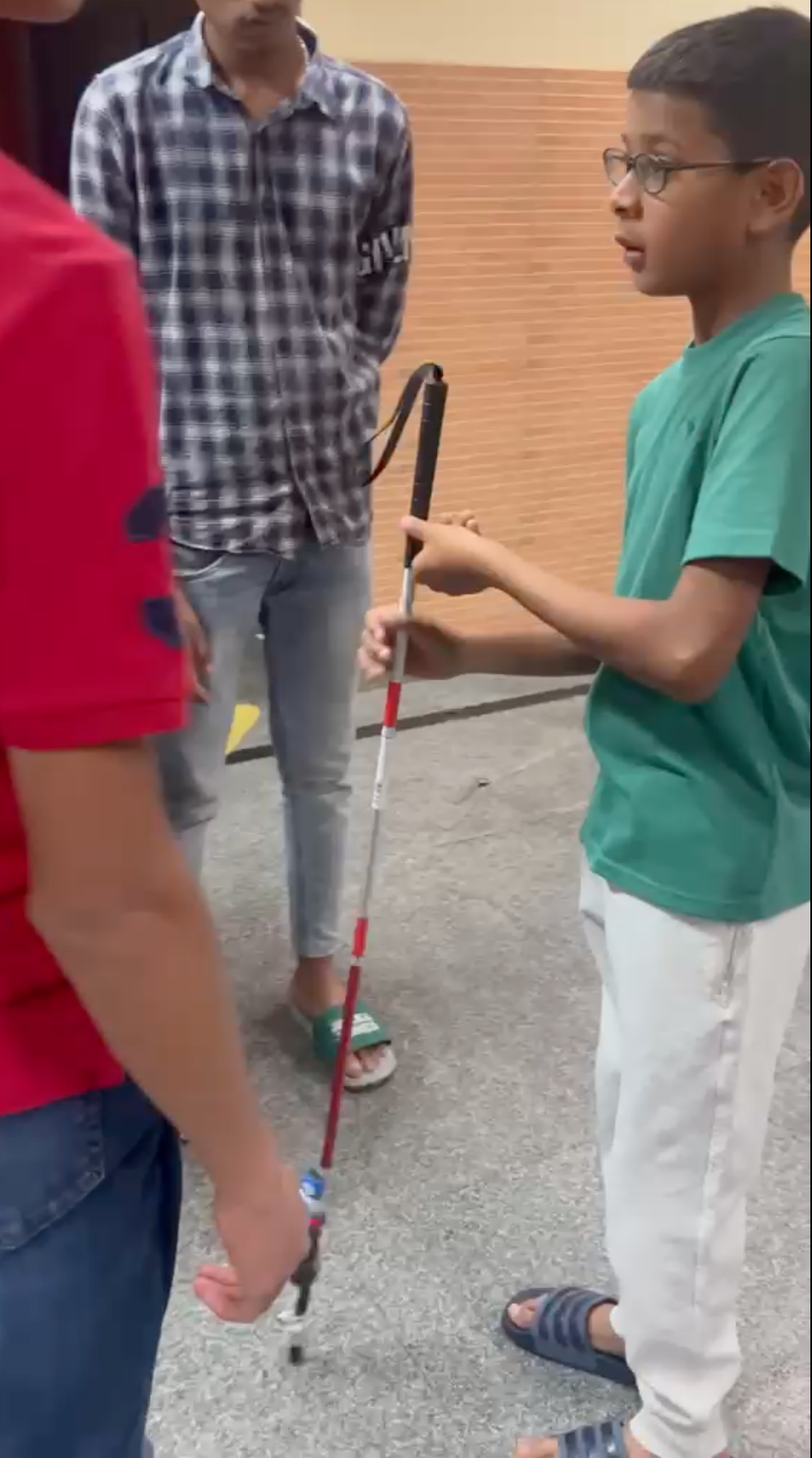 Vanij handing a completed smart blind stick to a student at Sri Rakum School for the Blind
