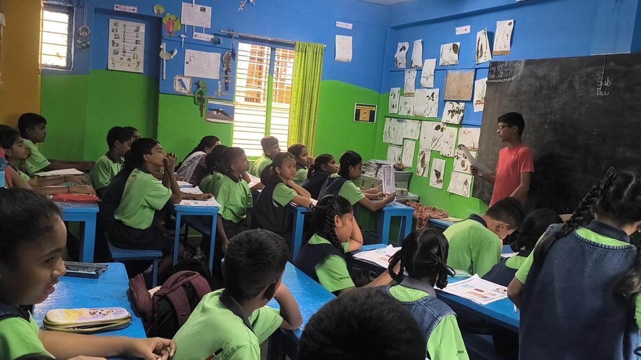 Vanij holding a worksheet at the front of the class as students work through it