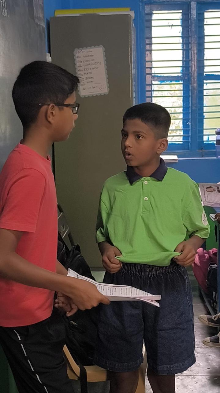 A student performing a line in front of Vanij, who holds the script